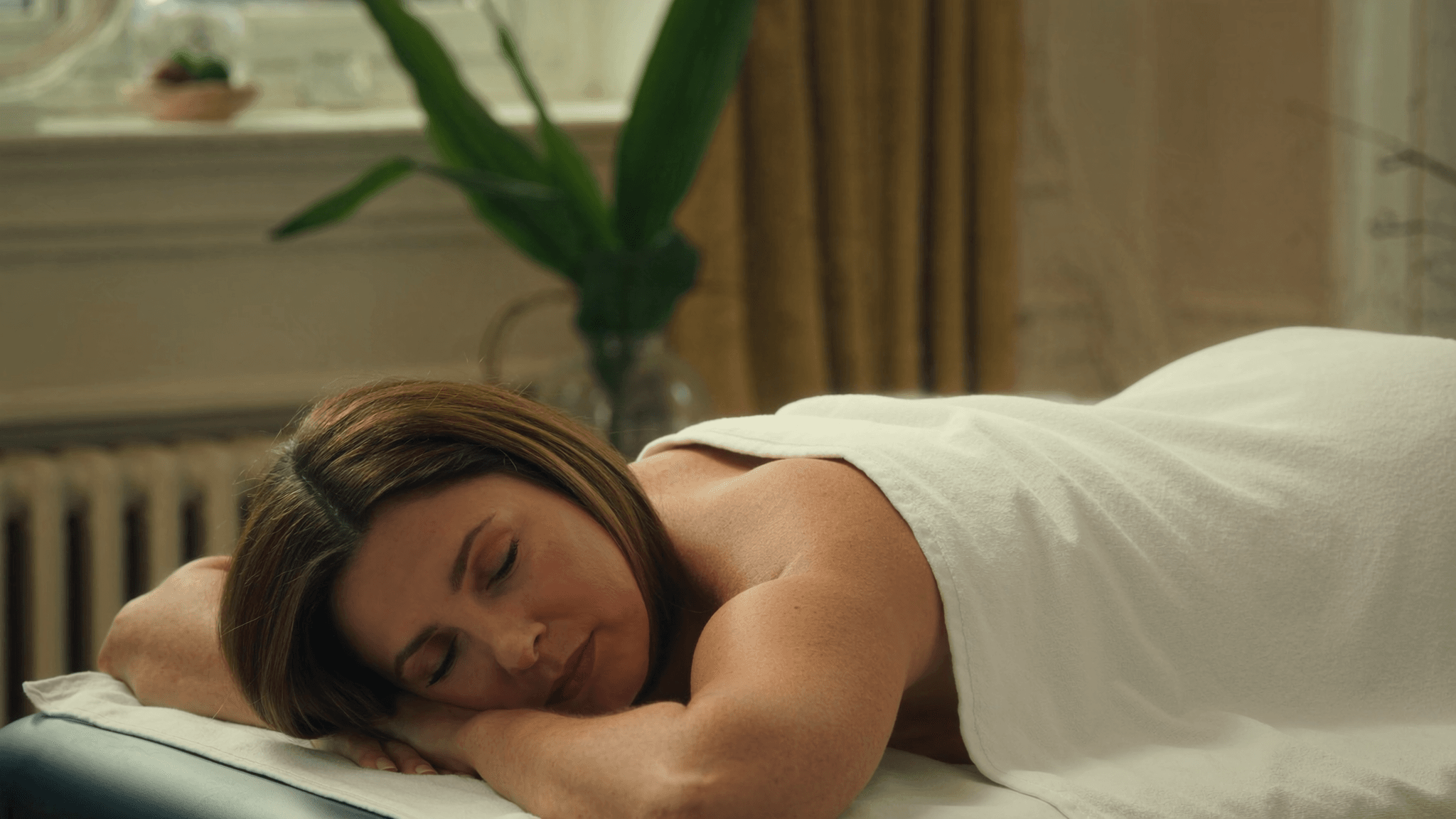 Relaxed woman resting on a couch during a massage therapy session in a calm treatment room.