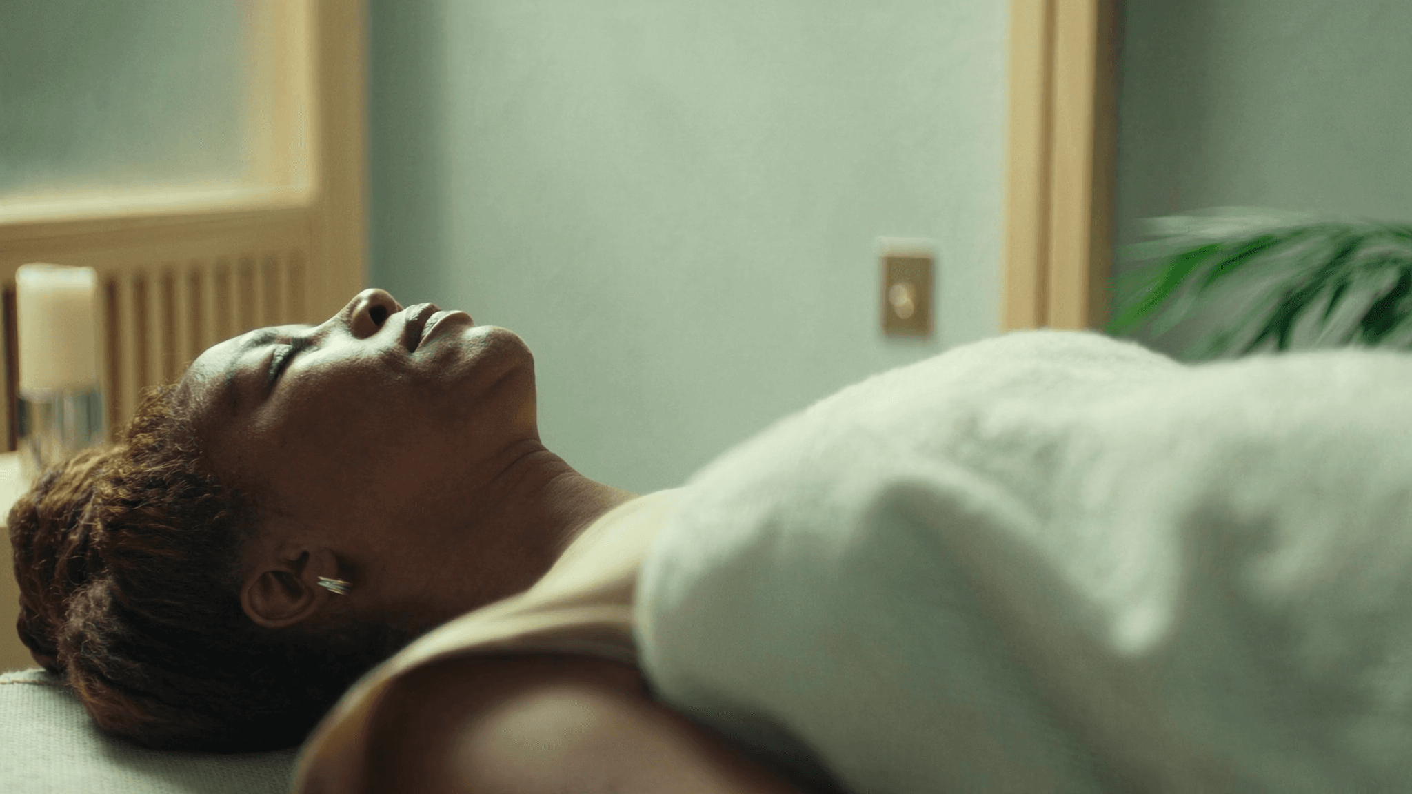 Relaxed woman resting fully clothed on a couch during a calm reiki relaxation session in a softly lit room