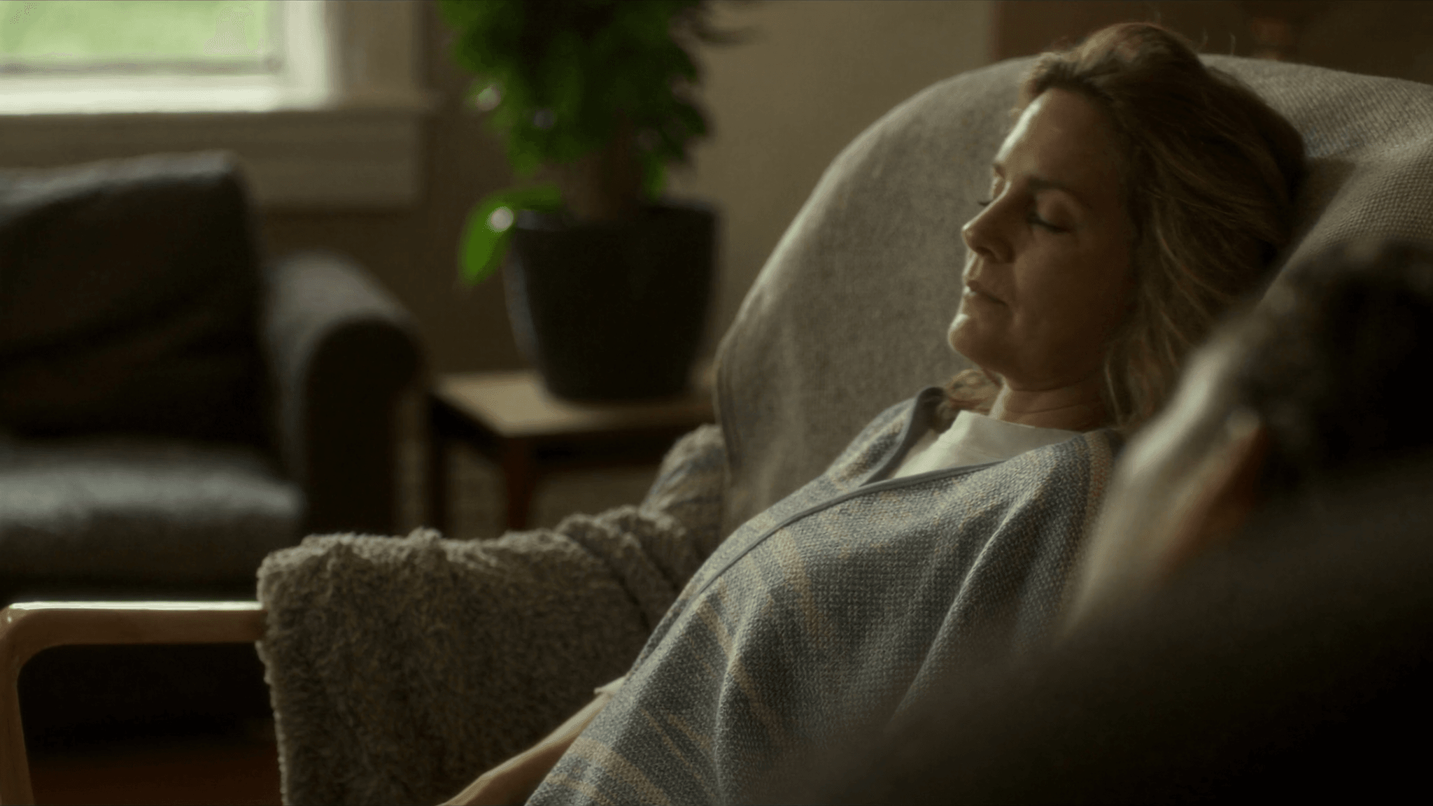 Relaxed woman resting with eyes closed in an armchair, showing what to expect at a hypnotherapy session.