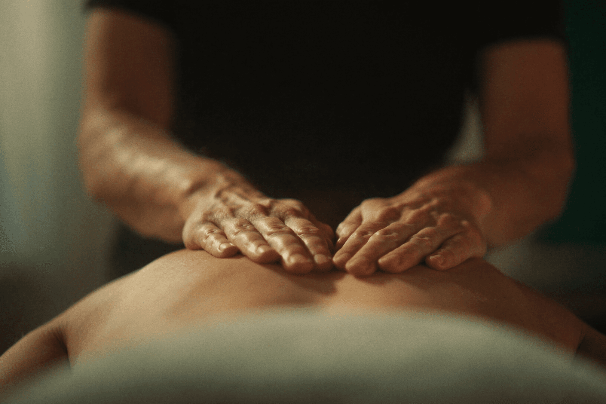 Practitioner's hands resting on a relaxed back, showing the benefits of a gentle massage.