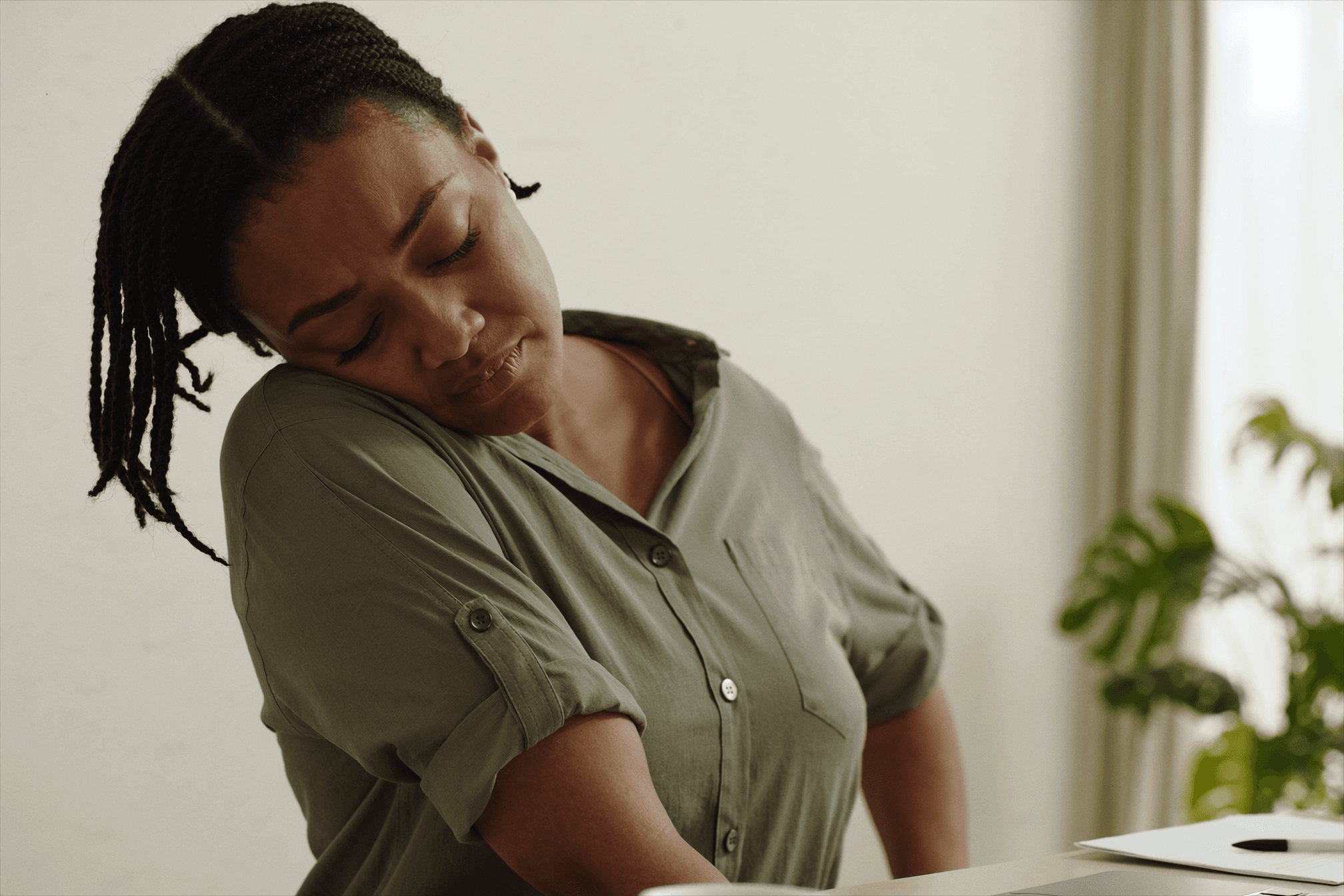 Woman stretching her neck and shoulders away from a laptop to ease desk-related muscle tension