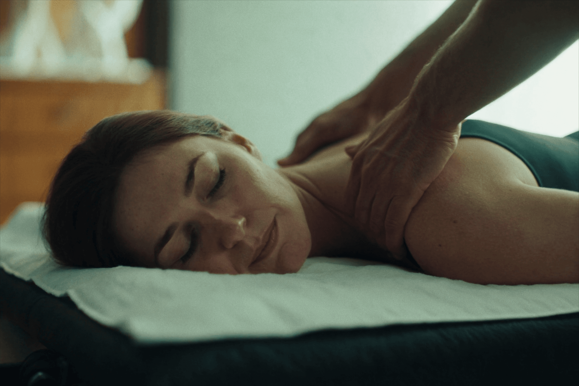 Steady focused pressure applied to a client's upper back to release a muscle knot during massage