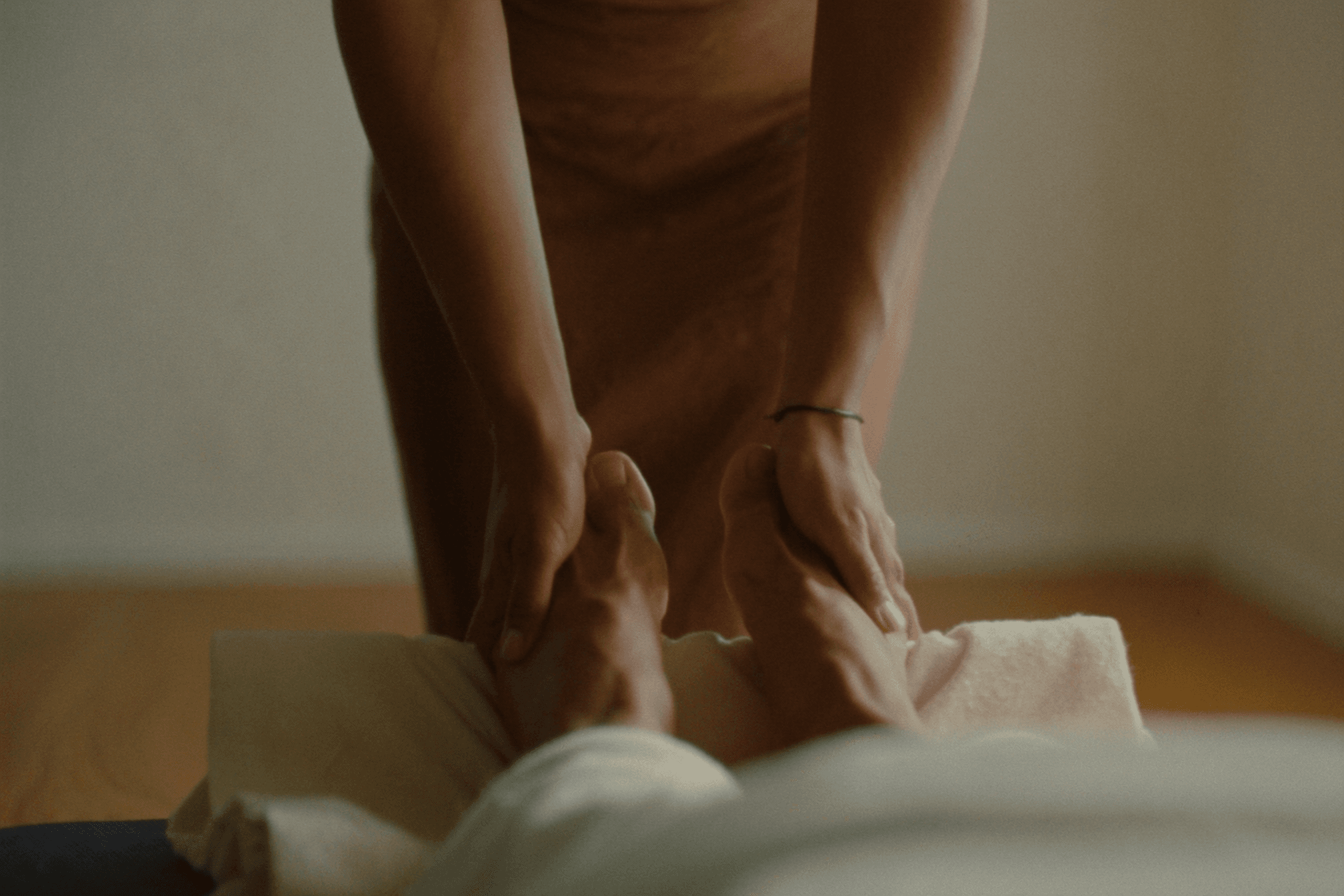 Bare feet resting on a towel with a therapist's hands nearby during a calm reflexology massage