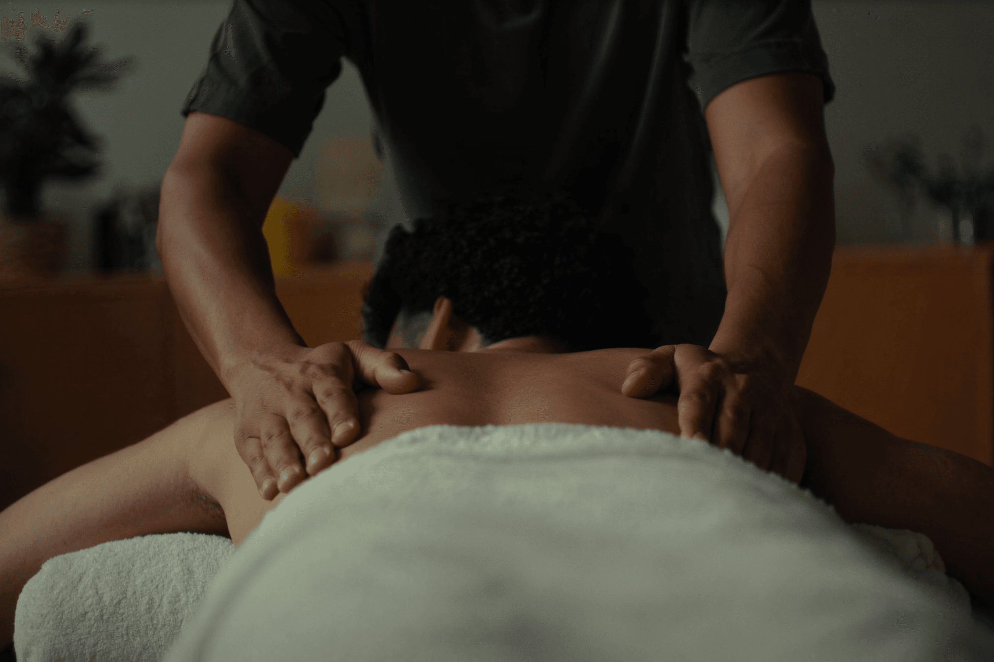 Massage therapist working gently across a relaxed client's shoulders in a calm treatment room during a Swedish massage